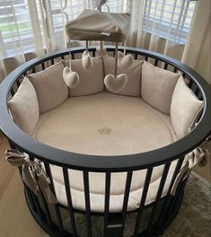 a baby crib that has hearts on the top and bottom, in front of windows