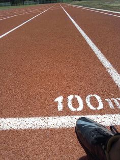 a person standing on a tennis court with the number 100 written in white lines behind them