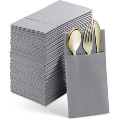 a stack of gray napkins with gold forks and spoons in them on a white background