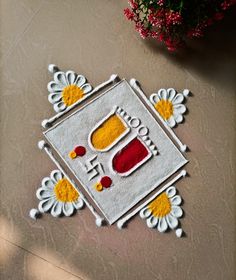 a white rug with yellow and red designs on it next to a potted plant