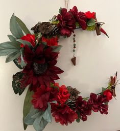 a wreath made out of red flowers and pine cones