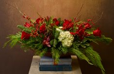 a bouquet of red and white flowers sitting on top of two blue books in front of a brown wall