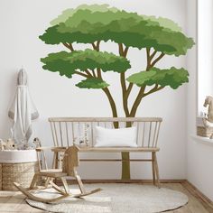 a child's room with a tree painted on the wall and rocking chair next to it