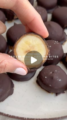 a person picking up a piece of chocolate covered banana from a plate with other pieces in the background