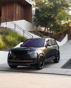 an suv parked in front of a house on the side of a road with stairs leading up to it