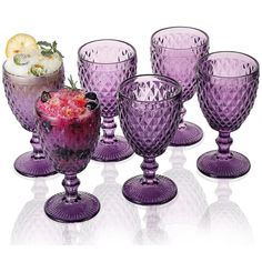 several purple glass goblets with fruit in them