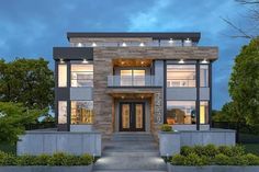 a large modern house with lots of windows and lights on it's front door