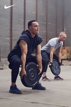 two men are doing squats with their weight plates