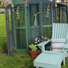 a blue lawn chair sitting in front of a green arbor with flowers growing on it