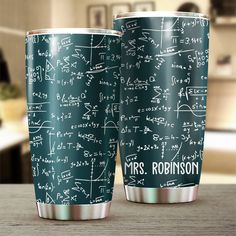 two coffee cups sitting on top of a wooden table covered in math symbols and calculations