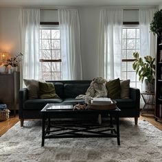 a living room filled with furniture and windows covered in white drapes on top of them