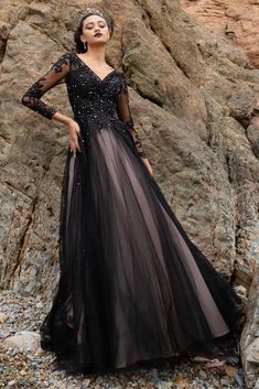 a woman in a black dress standing on rocks