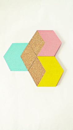 an arrow made out of cork on top of a white surface with yellow and pink squares