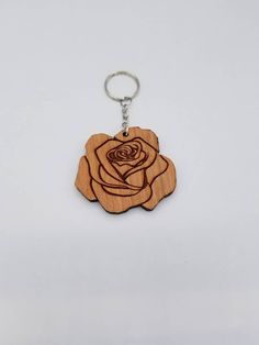 a wooden keychain with a rose engraved on the front and back, sitting on a white surface