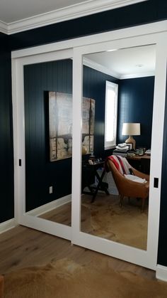 a living room with blue walls and white trim on the sliding glass doors that lead to an office