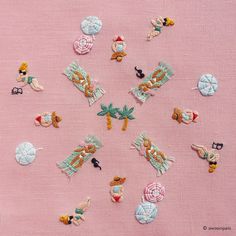 many small embroidered objects are arranged on a pink surface