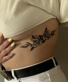 a woman's stomach with a flower tattoo on her left side ribcage