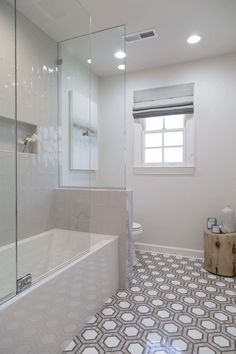 a bathroom with white walls and flooring has a glass shower door that opens up to the bathtub