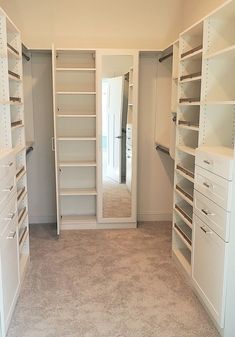 an empty walk in closet with lots of shelves and drawers on either side of the door