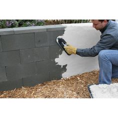 a man is painting the side of a wall with white paint and yellow gloves on