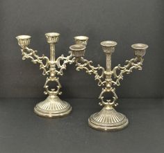 two silver candelabra candlesticks with chains on the sides and one candle holder in the middle