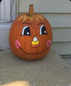 a pumpkin with an angry face painted on it's side sitting in front of a house