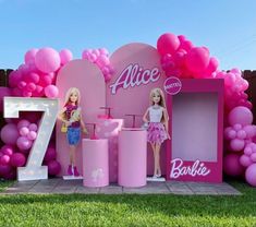 barbie doll display in front of pink balloon arch with number seven on the wall and two dolls standing next to it