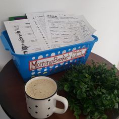 a cup of coffee sitting on top of a table next to a potted plant