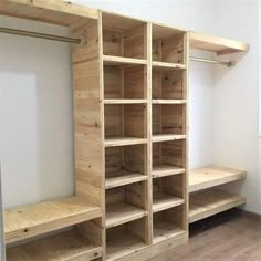 an empty closet with wooden shelves and drawers in it, next to a white wall