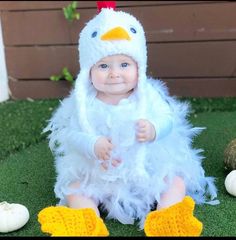 a baby in a chicken costume sitting on the grass