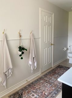 three towels hanging on the wall next to a toilet and sink in a room with white walls