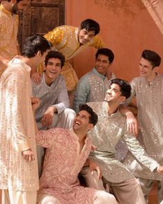 a group of young men standing next to each other in front of a wall and smiling