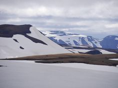 the mountains are covered in snow and brown grass