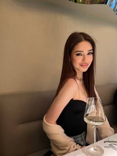 a woman sitting at a table with a glass of wine