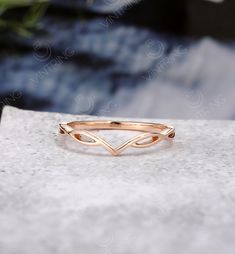 a gold ring sitting on top of a white stone table next to a potted plant