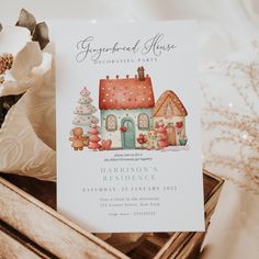 a white card with a gingerbread house on it next to flowers and other decorations