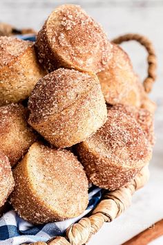 a basket filled with sugared donuts on top of a blue and white checkered cloth