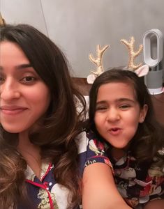 a woman and her daughter wearing reindeer antlers on their head, sitting next to each other