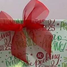 a wrapped present box with red ribbon and writing on the wrapping paper that says no pecking until 25 cents