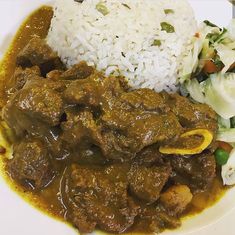 a white plate topped with rice and meat next to cabbage covered in gravy