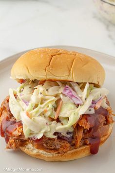 a pulled pork sandwich with coleslaw and slaw on a white platter