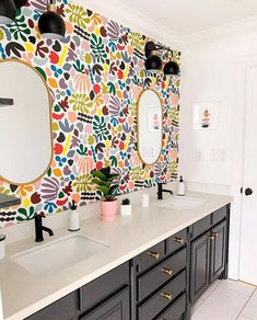 a bathroom with two sinks, mirrors and wallpaper on the walls in different colors