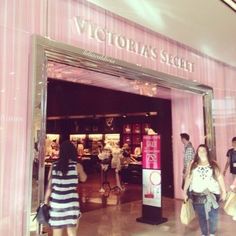 people walking in front of victoria's secret store with pink curtains on the wall