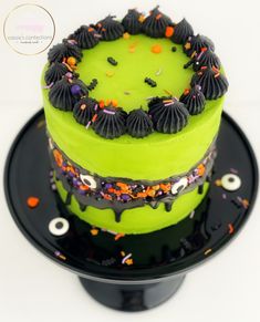 a green cake with black icing and sprinkles