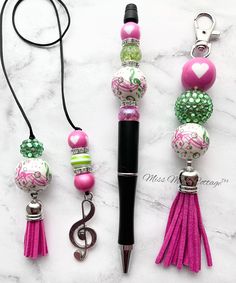 three different types of beads and keychains on a marble surface with a black pen