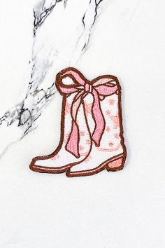 a pair of pink boots with a bow on the side sitting on a marble surface