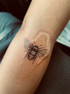 a tattoo on the arm of a woman with a bee on it's side