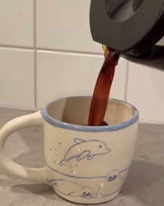 a coffee cup filled with liquid being poured into it