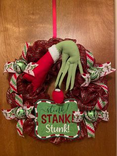 a christmas wreath with an elf's hand hanging from the front door, and a sign that says stay stakk stink