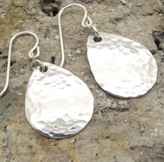 "These lightweight small hammered teardrop earrings are made from solid sterling silver. We have four sizes of tear drop earrings, and these are the small, 1-1/4 inch long size. I have textured them with a hammer, cupped them to give them a bit of a dome shape, and tumble polished them for shine and strength. These earrings are hung with several extra links. The links make the teardrops move gracefully and fit more comfortably. The widest part of the teardrop is about a 3/4\" (17 mm) and the len Hammered Sterling Silver, Disc Earrings, Jewelry Studio, Hammered Silver, Single Earring, Light Weight Earrings, Round Earrings, Teardrop Earrings, Beautiful Earrings